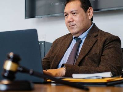 Avocat en costume sombre assis à son bureau devant un ordinateur portable, livres de droit en arrière-plan