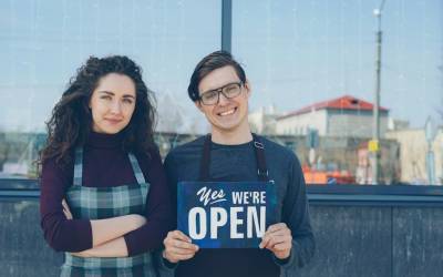 Fiche Google Business Profile : deux commerçants devant leur boutique avec un panneau ouvert